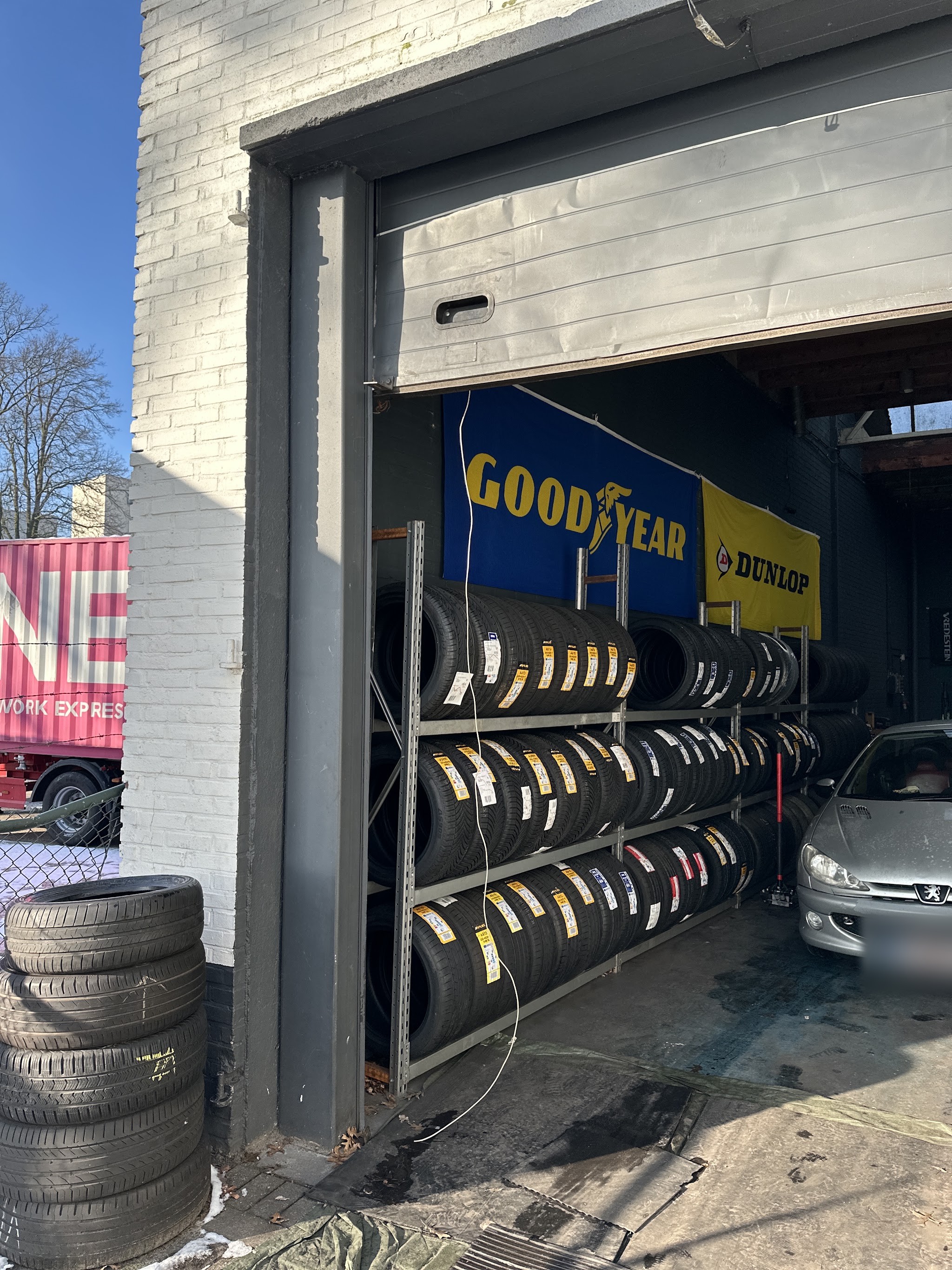 De open roldeur van de werkplaats met een stelling vol banden